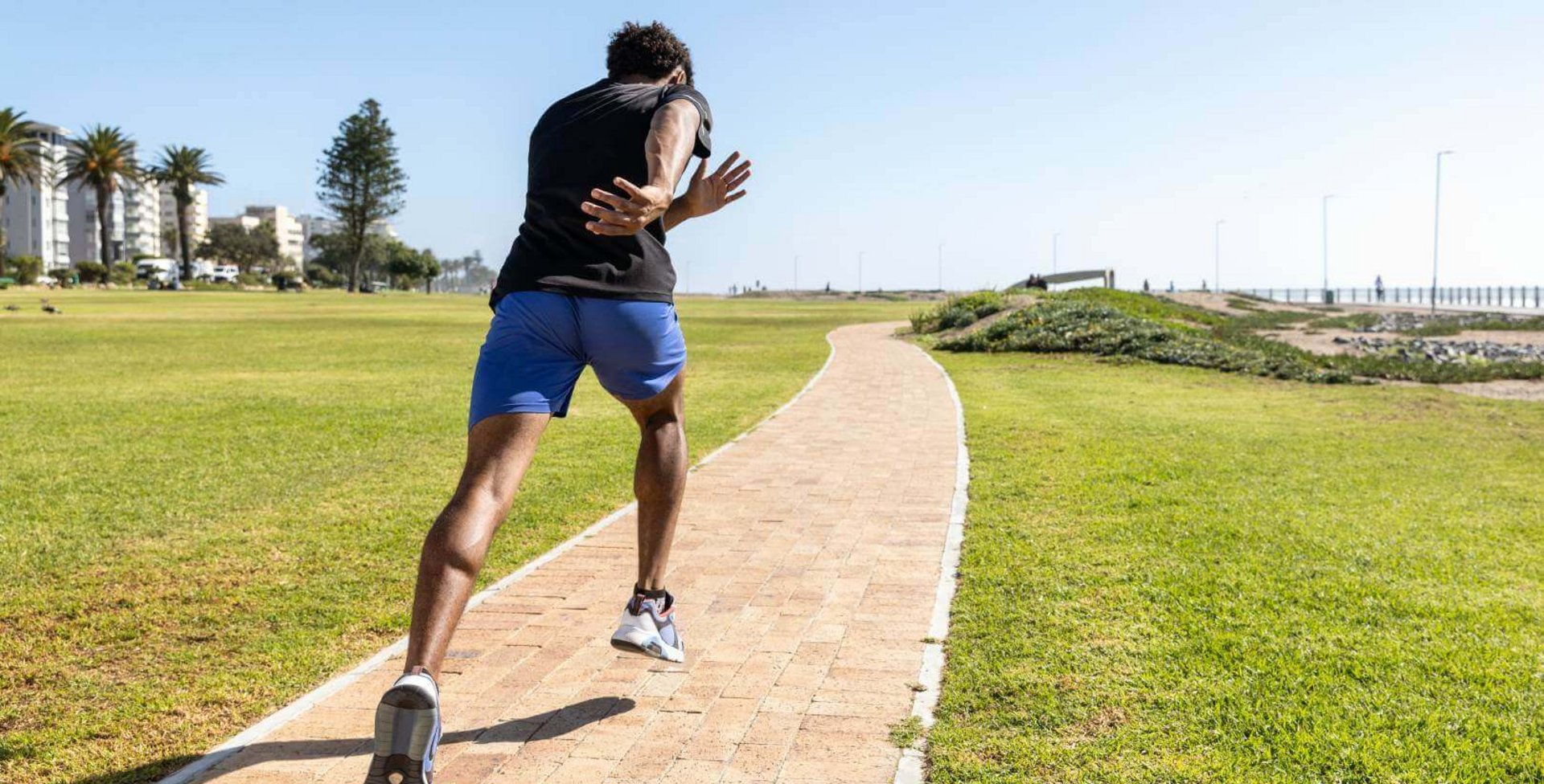 Das Bild zeigt einen dynamischen Läufer, der mit großen Schritten einen Parkweg entlangläuft.