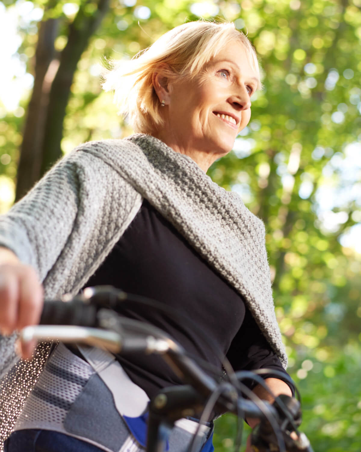 Eine Frau fährt auf einem Fahrrad. Sie trägt währenddessen eine Rückenbandage von Bauerfeind.