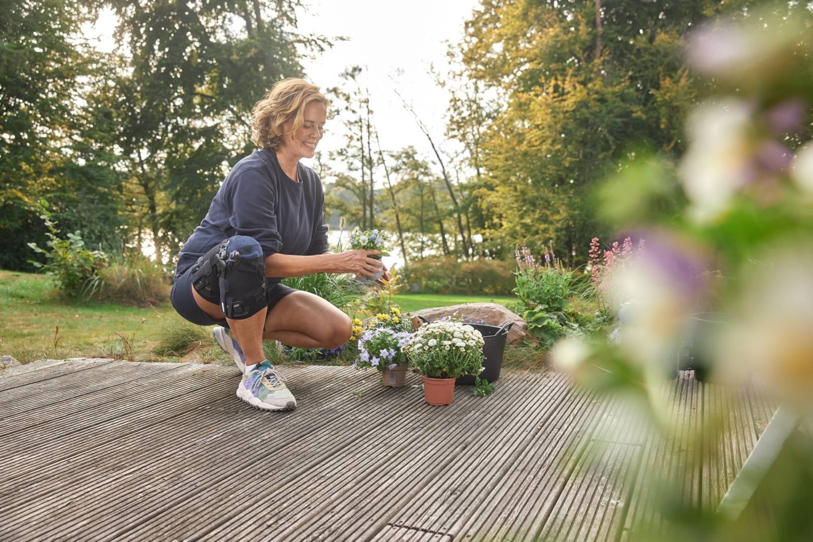 Leichtes Joggen bei Kniearthrose Eine Frau kniet während der Gartenarbeit und trägt dabei eine GenuTrain OA Orthese zur Unterstützung.